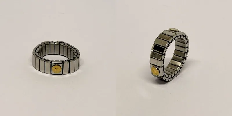 Anel prateado de aro largo em malha articulada com medalhão dourado discreto